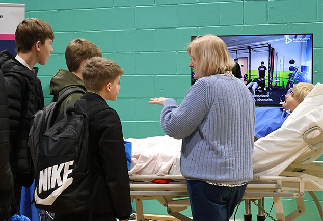School students speaking to College teacher in hall