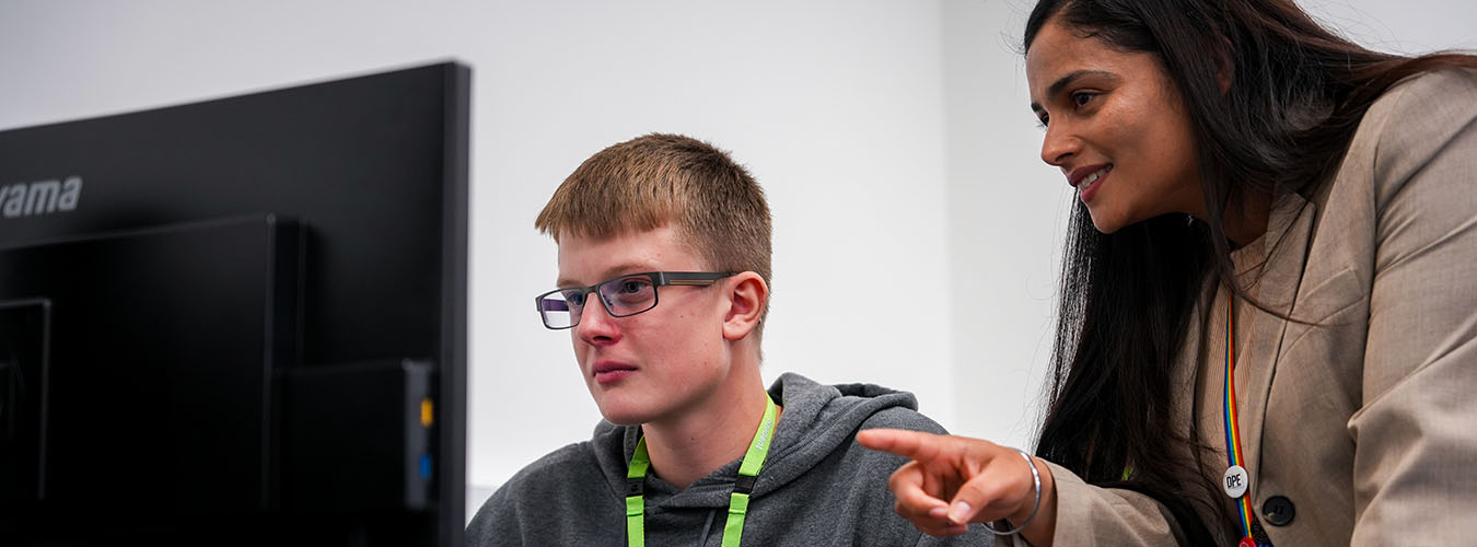 Teacher standing next to student using computer