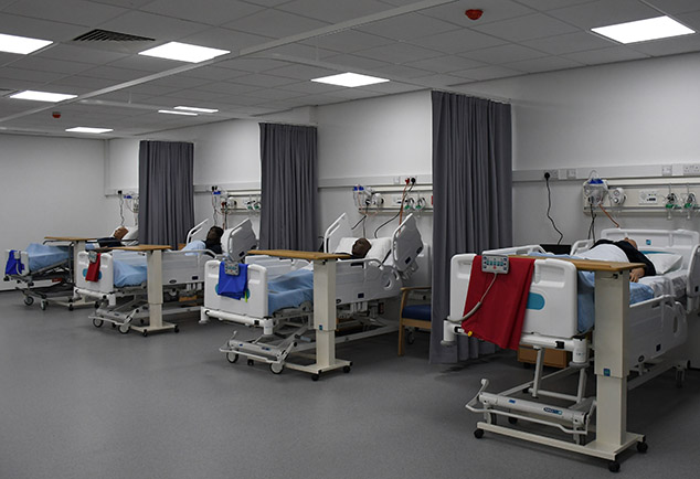 Mock hospital ward with beds and mannequins 