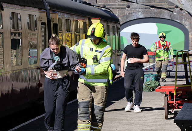 Students in mock emergency simulation at train station acting as injured travellers or emergency service personnel  