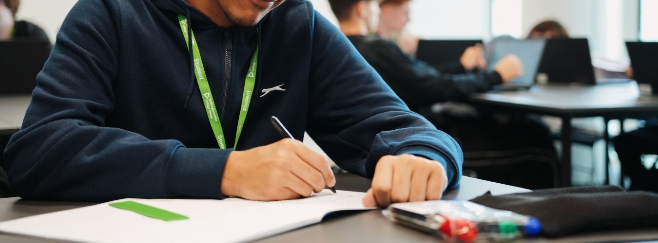 Student sitting at desk writing in book