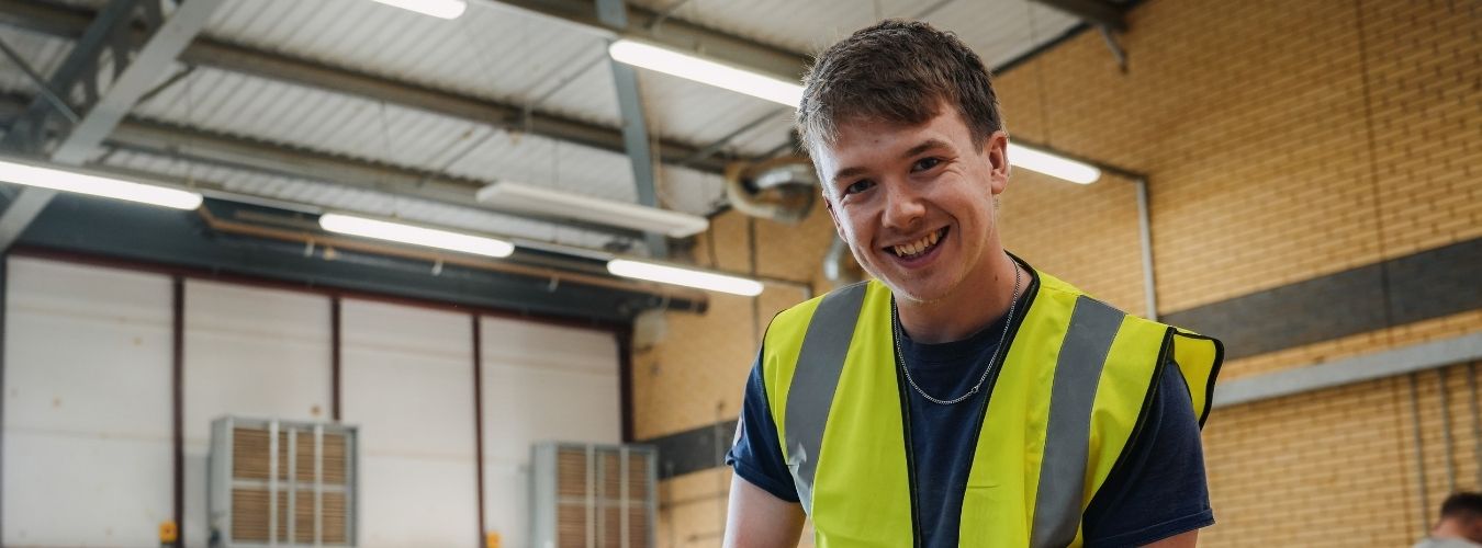 Student wearing hi-vis and smiling at camera
