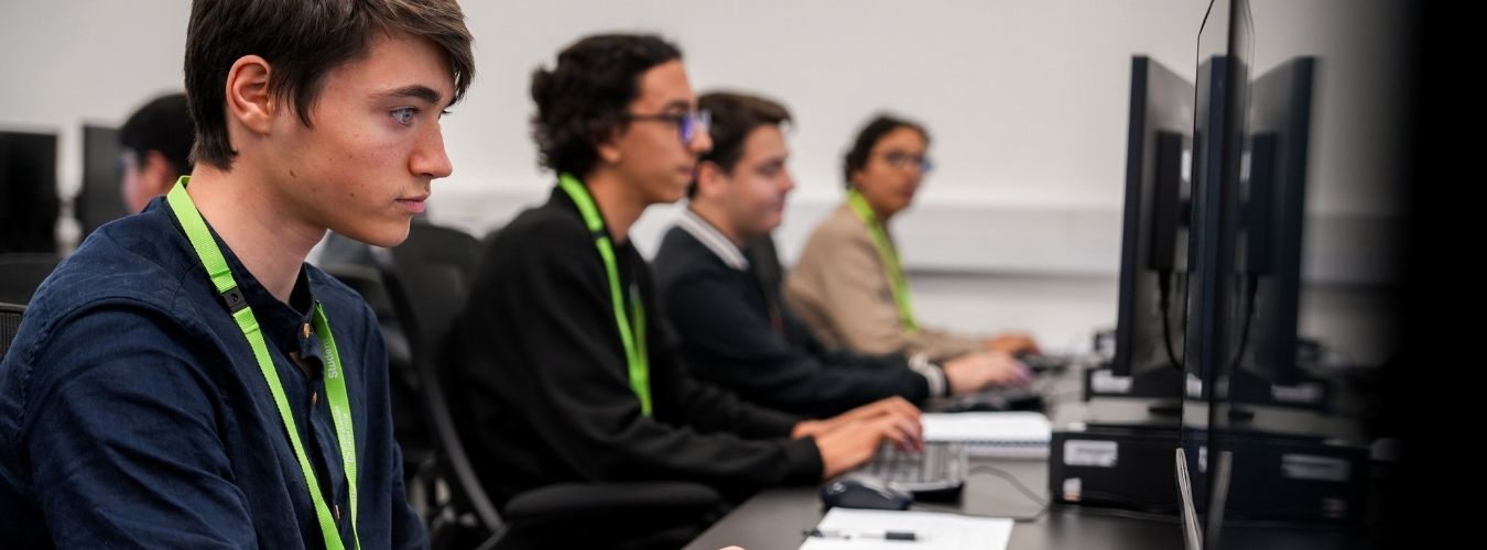 Students sitting in front of a row of computers