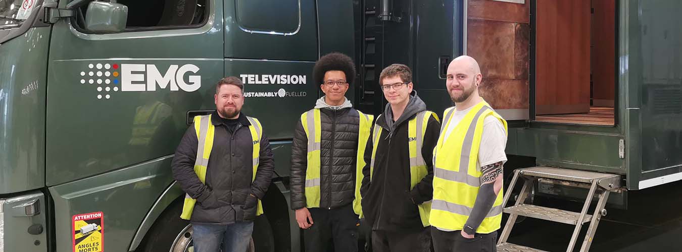 Students standing with employers in front of TV production truck with EMG logo