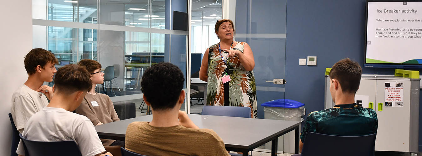 Teacher in classroom speaking to group of students around a table