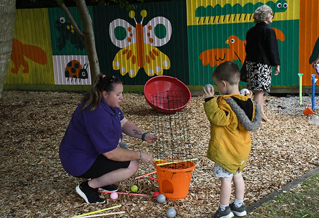 Child playing in nursery garden with teacher