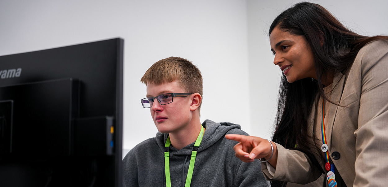 Teacher helping student on computer