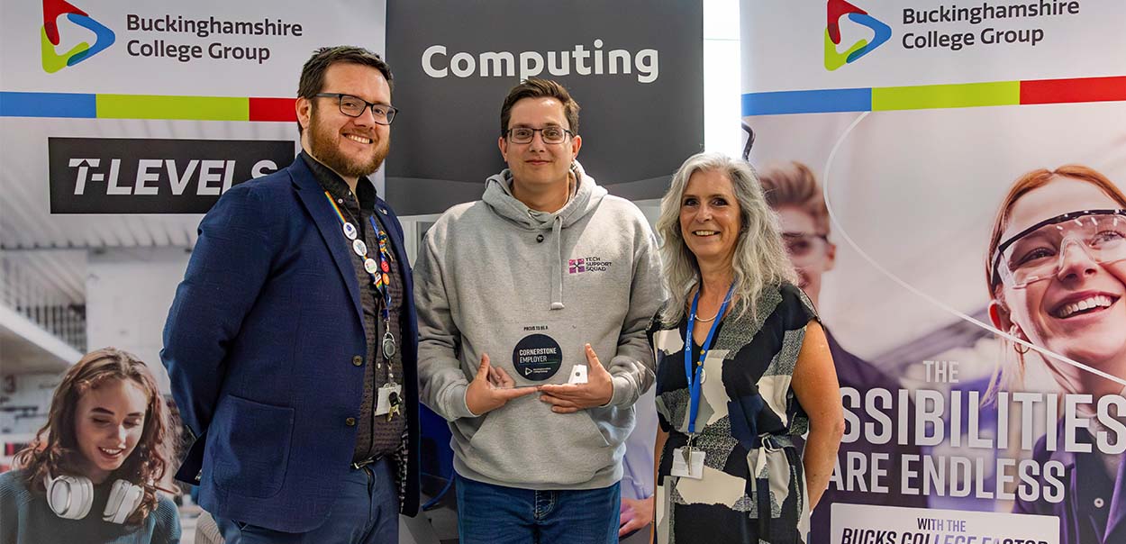 Two men and one women standing together looking at camera with one man holding plaque.